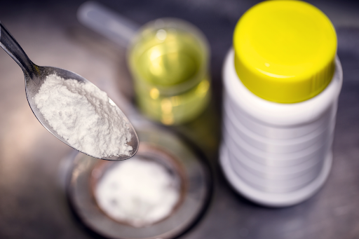 spoonful of baking soda with vinegar in background