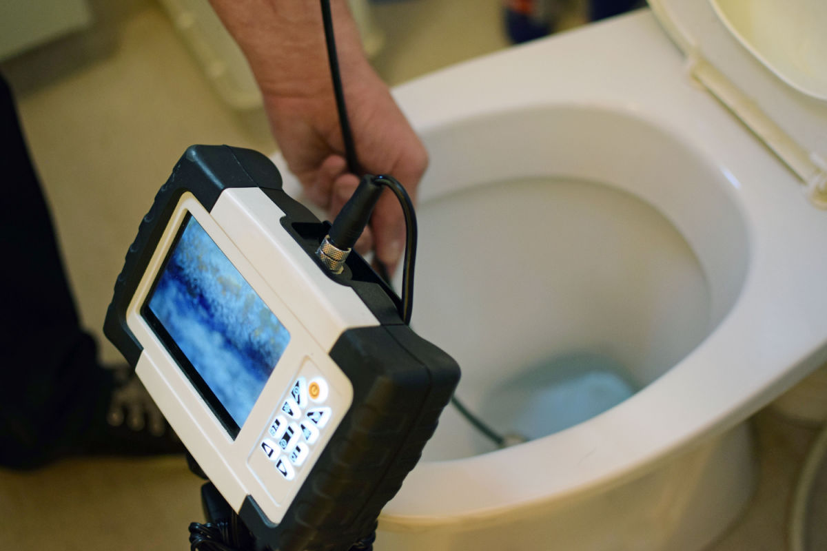 Professional plumber inspecting a clogged toilet with a sewer camera