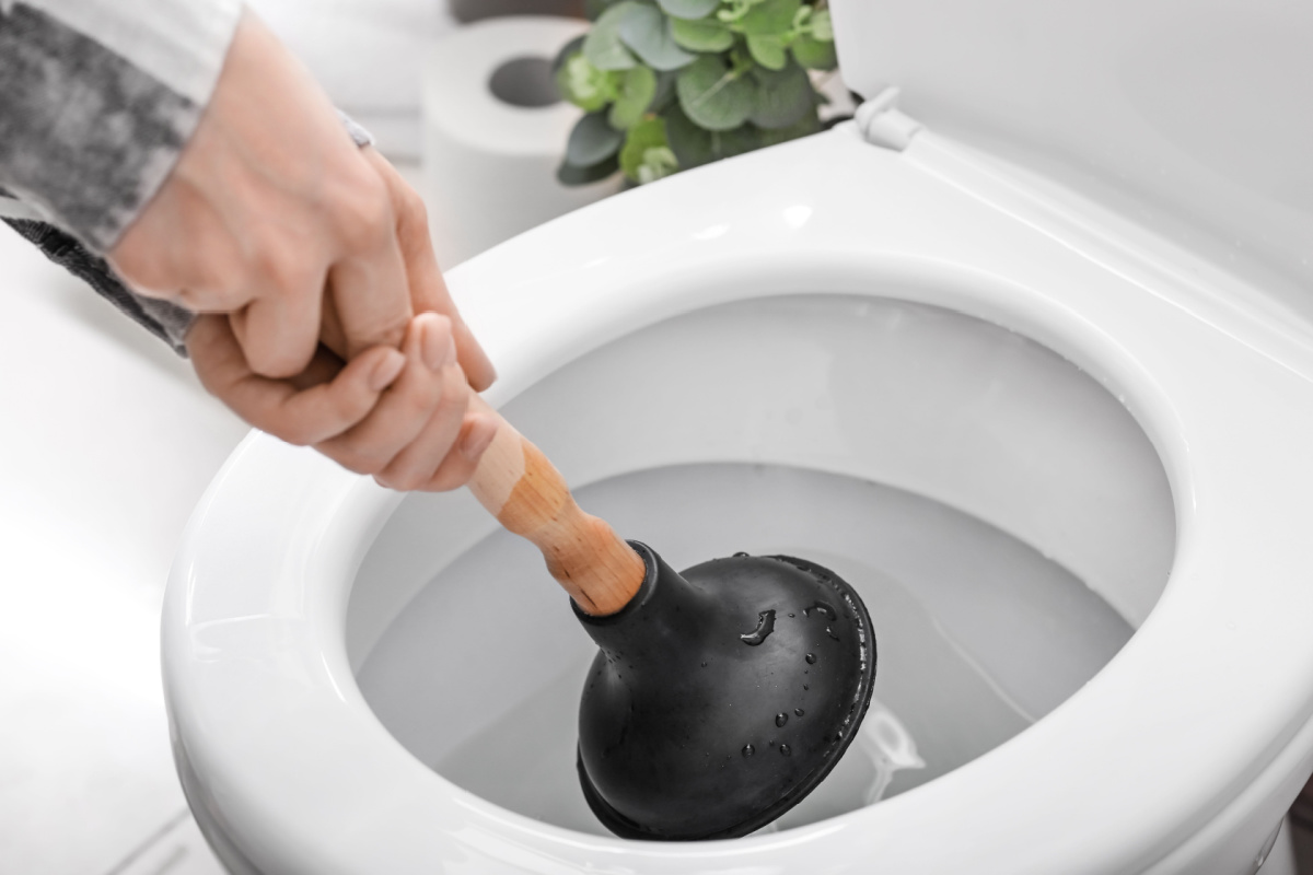 Homeowner plunging a clogged toilet