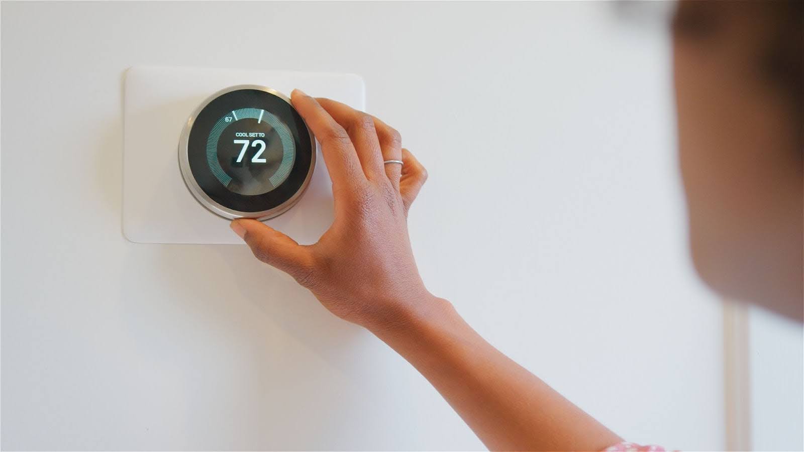 woman adjusting the temperature on the thermostat